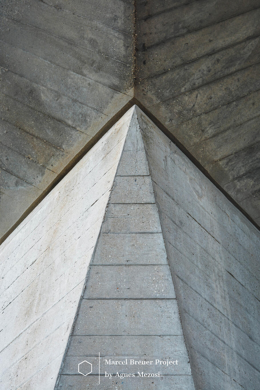 Extreme close-up of a structural concrete junction at the IBM Research Center. The image shows the sharp, geometric meeting point of the Y-shaped pilotis, highlighting the raw board-marked concrete texture and Marcel Breuer's sculptural engineering.