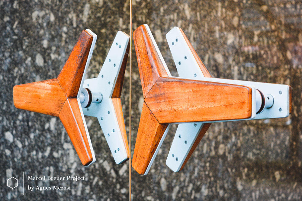 Close up shot of a unique, Y-shaped wooden door handle on a glass door, reflecting the attention to detail in Breuer's interior design.