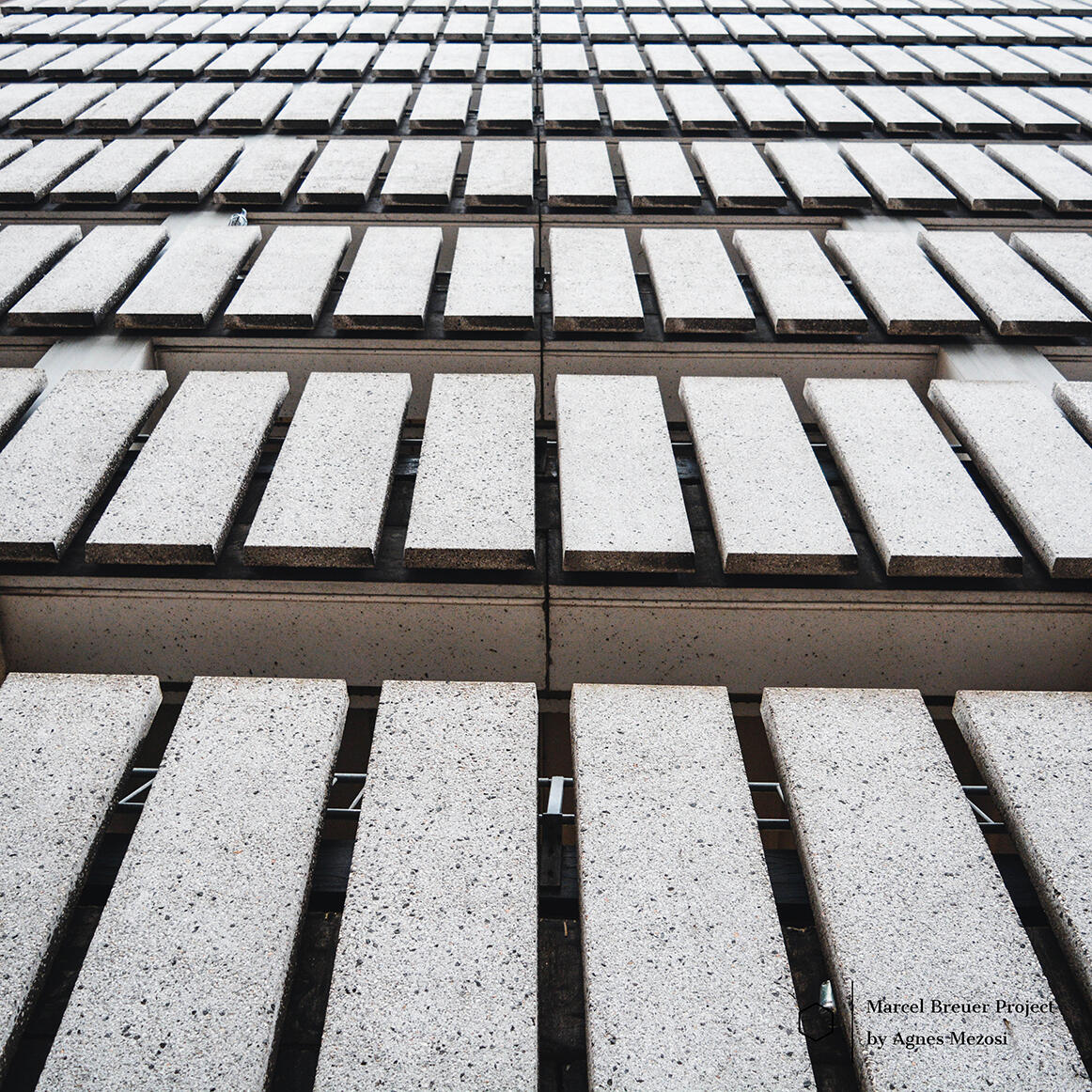 Close-up photograph of the textured concrete facade of the later-added parking structure at De Bijenkorf, designed to harmonize with Breuer's original modular style.