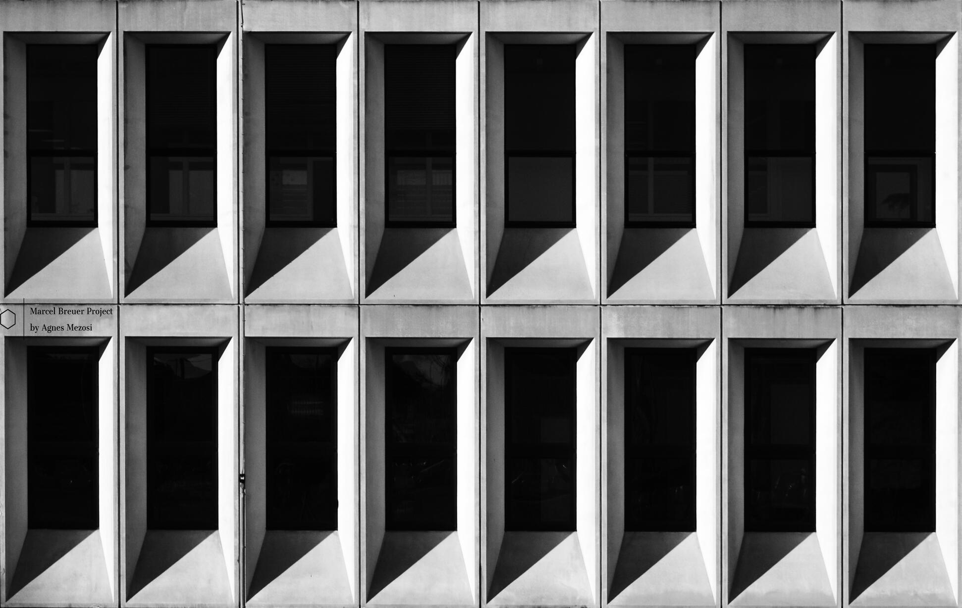 Symmetrical close-up of the repetitive, rectangular concrete window modules, showing a sharp contrast between light and dark.