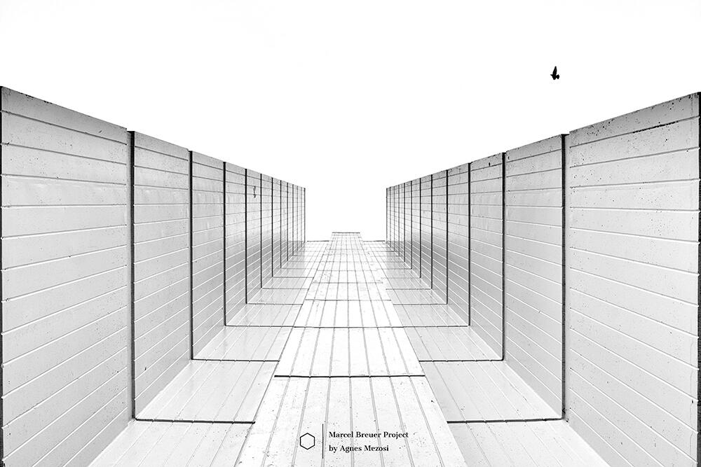 A dramatic low-angle shot looking straight up between two parallel white concrete walls, creating a symmetrical V-shape against a clear sky.