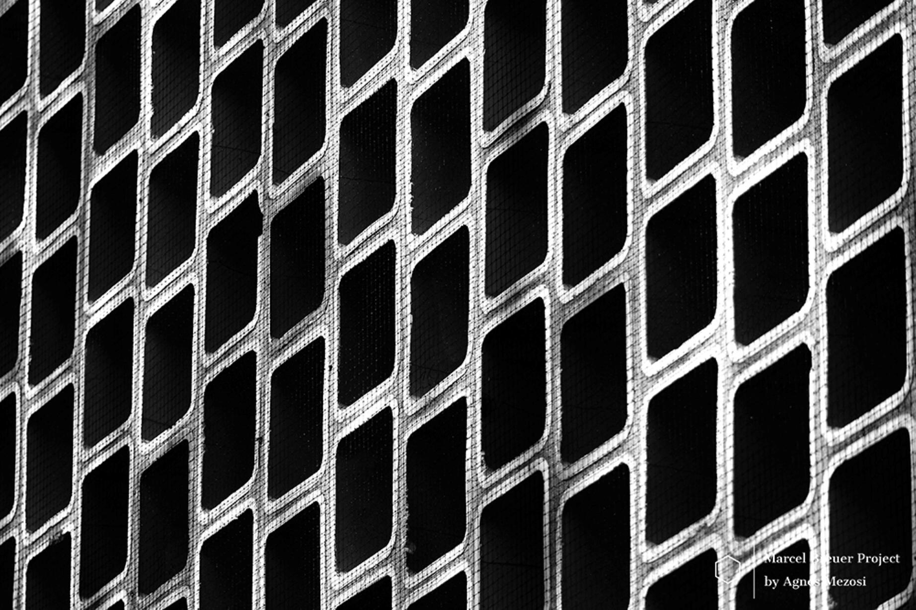 A high-contrast black and white close-up of the diamond-shaped concrete screen, creating a mesmerizing abstract pattern.