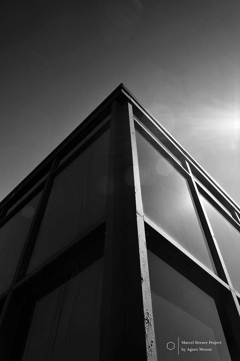 A dramatic low-angle black and white shot of the building's corner, showing the steel and glass structure pointing towards the sun.